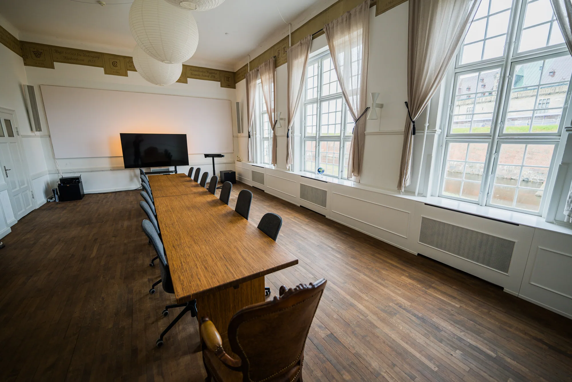 Det fulde mødelokale med langbord, skærm og udsigt til Kronborg